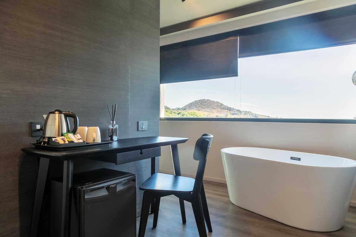 A modern room with a desk, chair, and a white bathtub.