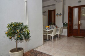 A dining area with a table and chairs, a potted plant, and a door leading to another room. - Il Vicolo B&B (Milazzo)