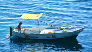 Ein Boot mit einem gelb-weiß gestreiften Verdeck, Flaggen und Rettungsbojen.