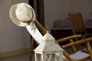 Una sedia di legno rustica con un lanternino bianco e un cappello di paglia appoggiato sopra.