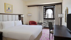 A hotel room with a large bed, a desk, a chair, a window with curtains, and a framed picture on the wall. - Intercontinental Madinah - Dar Al Iman by IHG (Madinah)