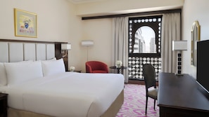 A hotel room with a large bed, a desk, a chair, a window with curtains, and a framed picture on the wall. - Intercontinental Madinah - Dar Al Iman by IHG (Madinah)