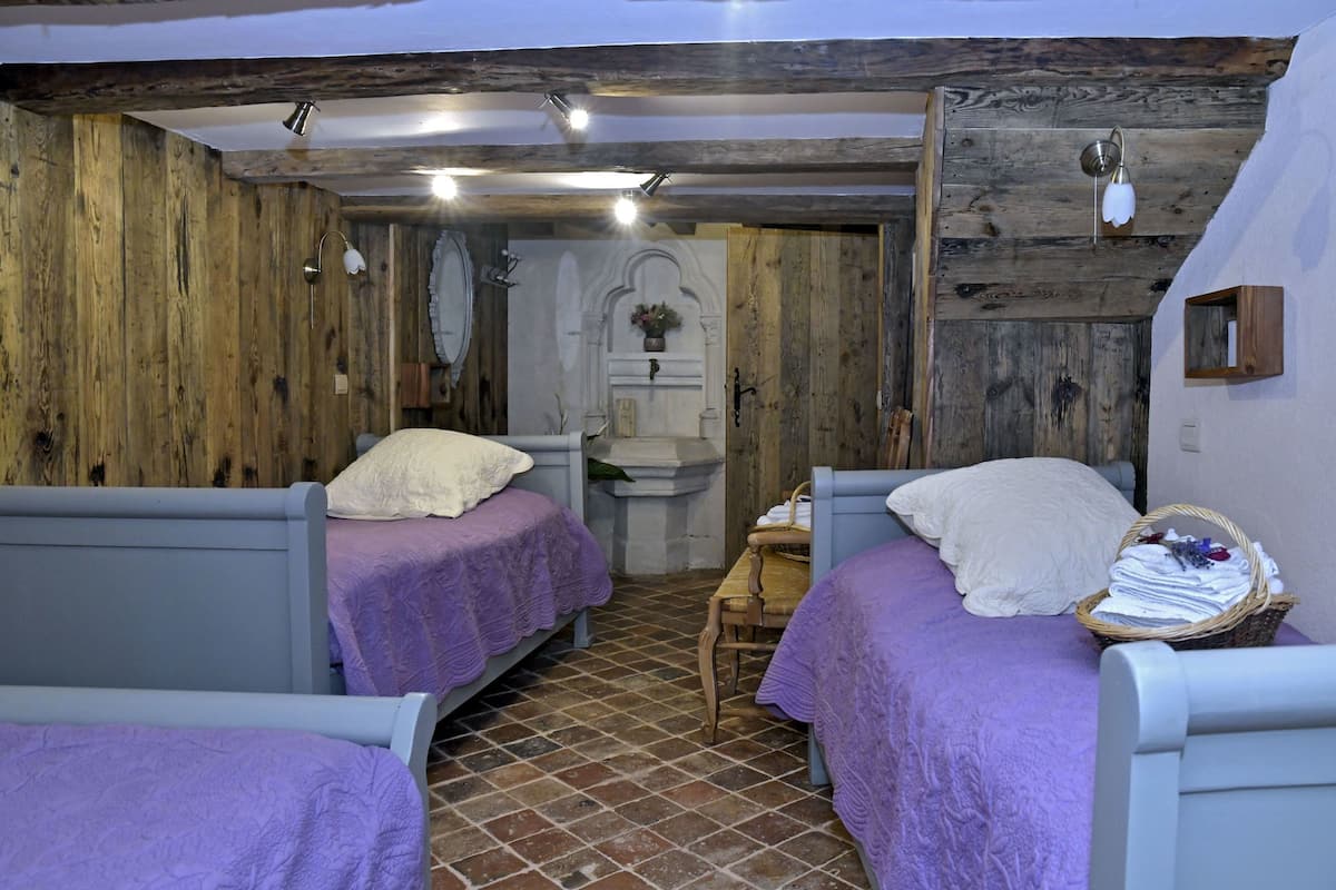 A rustic room with two beds, a wooden ceiling, and a small table with a basket.