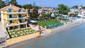 Un hotel frente al mar con piscina, sillas de descanso en la playa y vistas al océano.