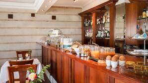 Una barra de desayuno con diversas opciones de comida y bebida, como huevos, jugo y una estación de café.