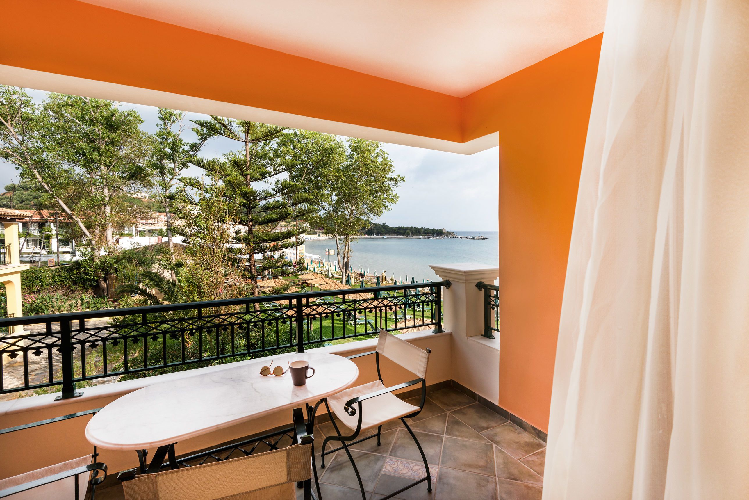 Un balcone con tavolo e sedie, vista sul mare e ringhiera.