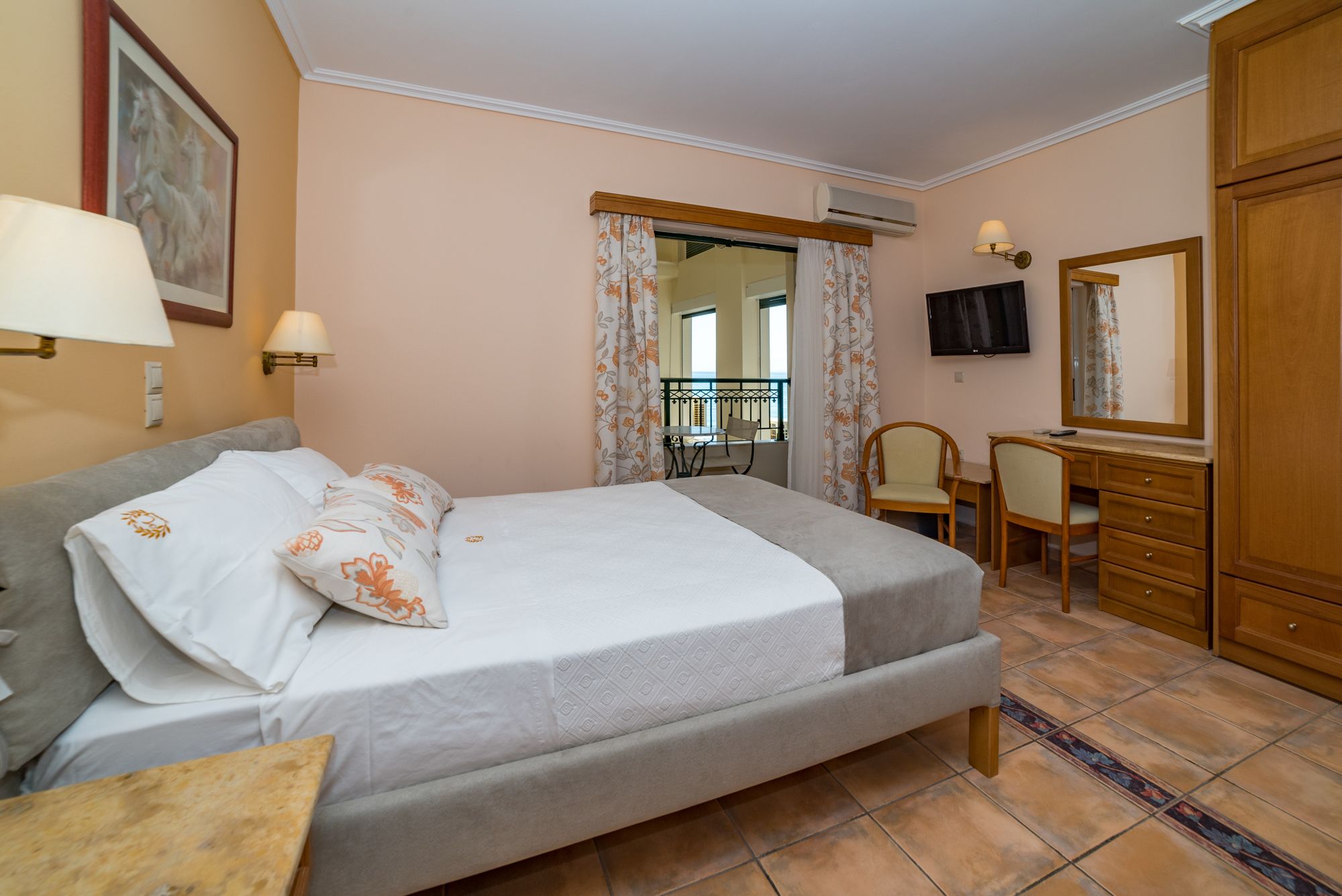 A hotel room with a bed, a desk, a chair, a TV, and a wardrobe.
