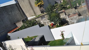 A modern building with a flat roof and a small garden area with a palm tree and flowers. - Sol da Nave (Porto)