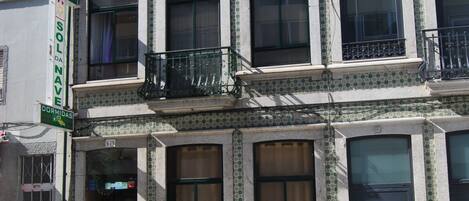 Un edificio de varios pisos con entrada a nivel de calle, ventanas amplias y un balcón.