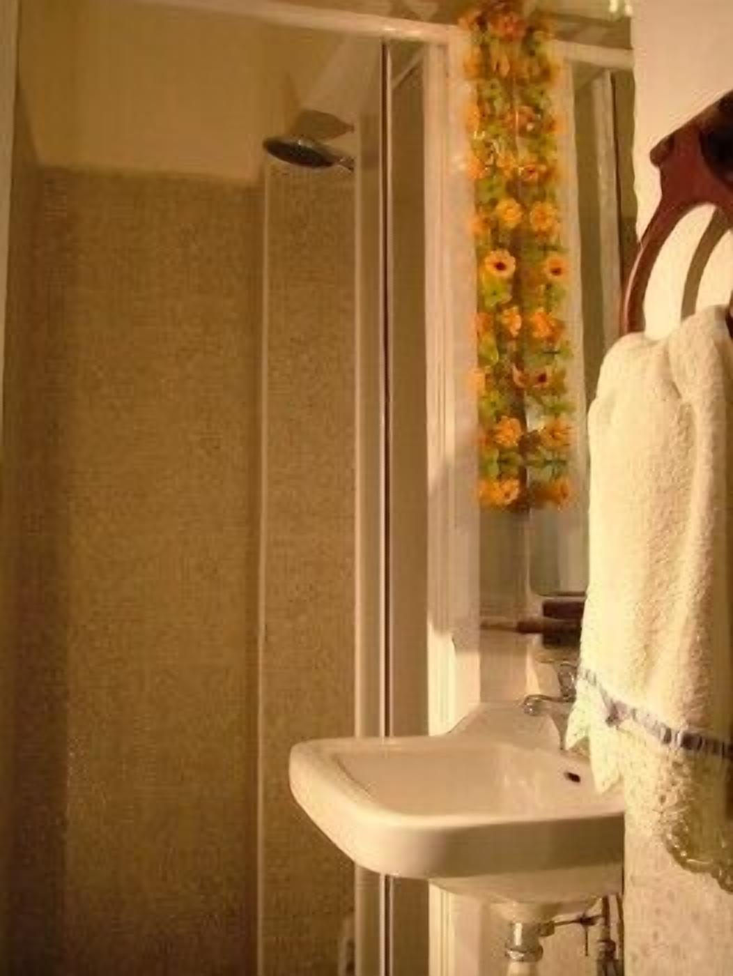 A bathroom with a shower, a sink, and a towel rack.