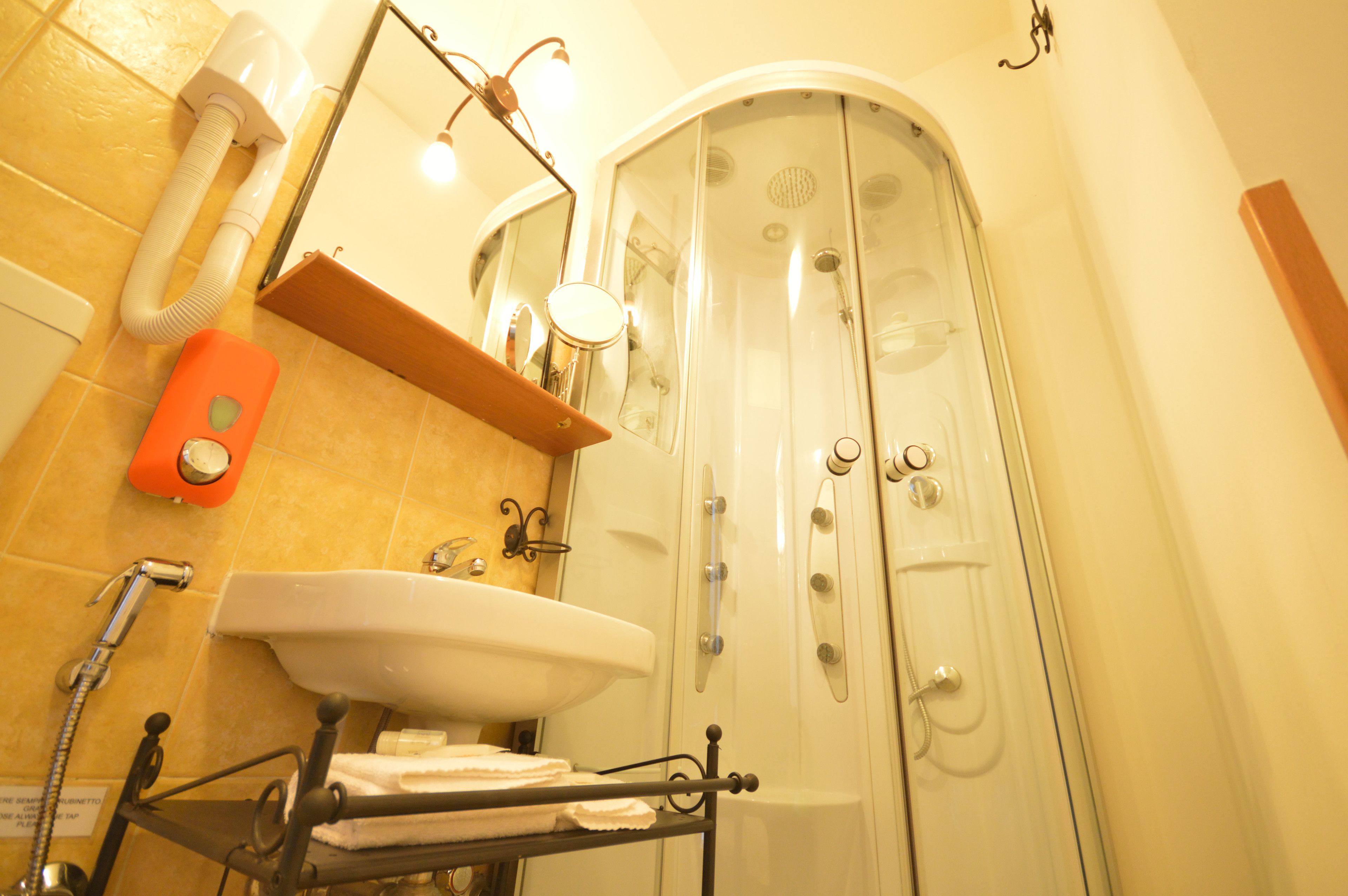Ein Badezimmer mit Waschbecken, Spiegel, Handtuchhalter, Dusche und Handtuchspender.