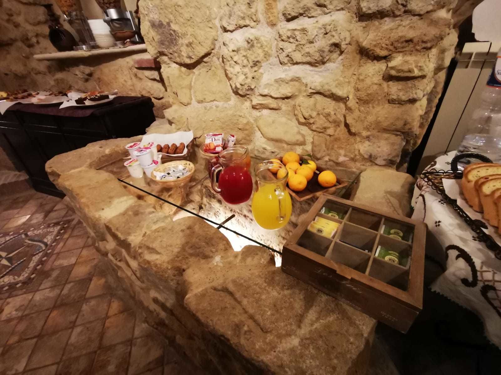 Eine Theke aus Stein mit Frühstücksangeboten, darunter Gebäck, Obst und Getränke.