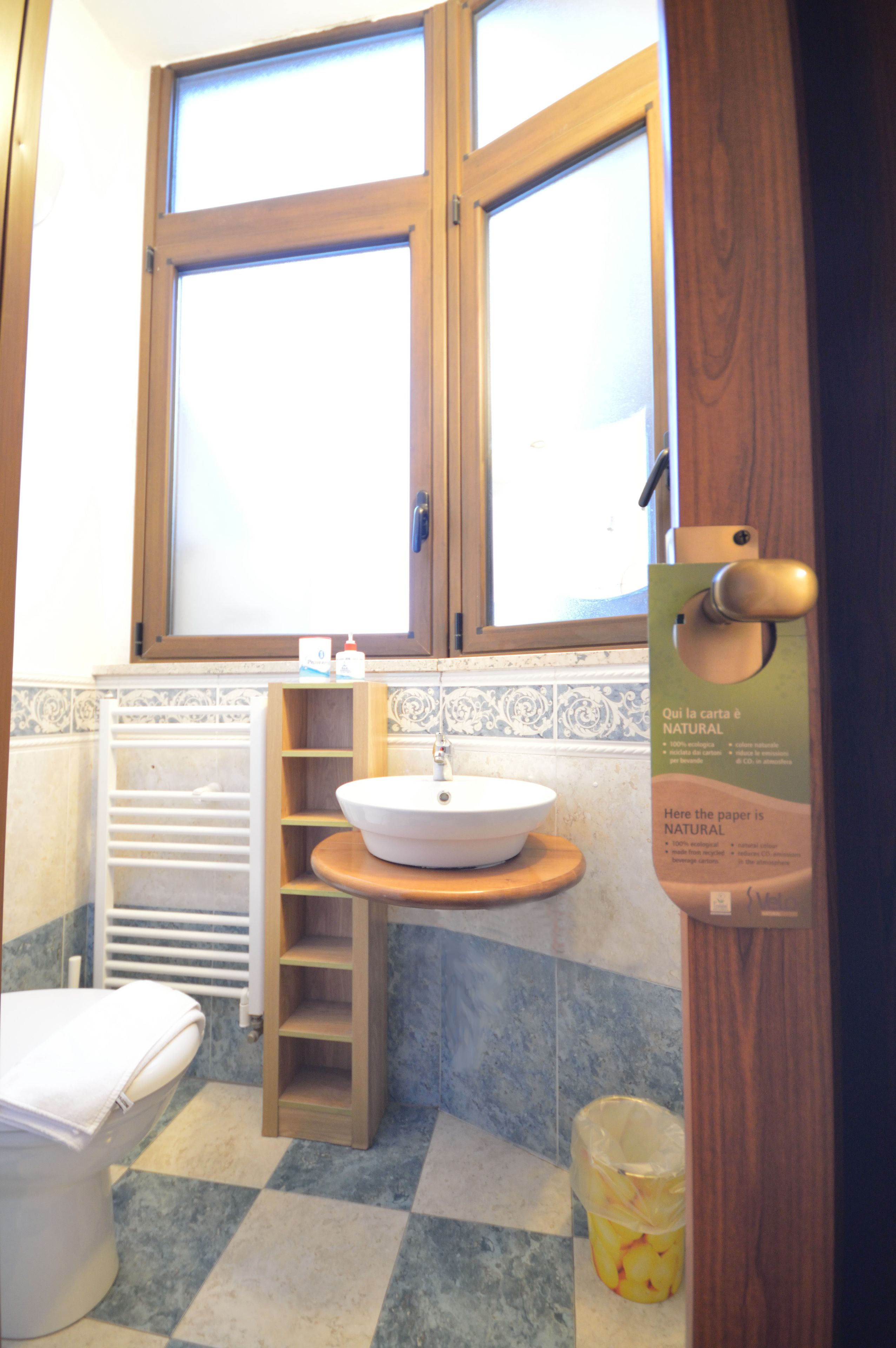Un baño con tocador de madera, lavamanos, inodoro y ventana sobre el lavamanos.