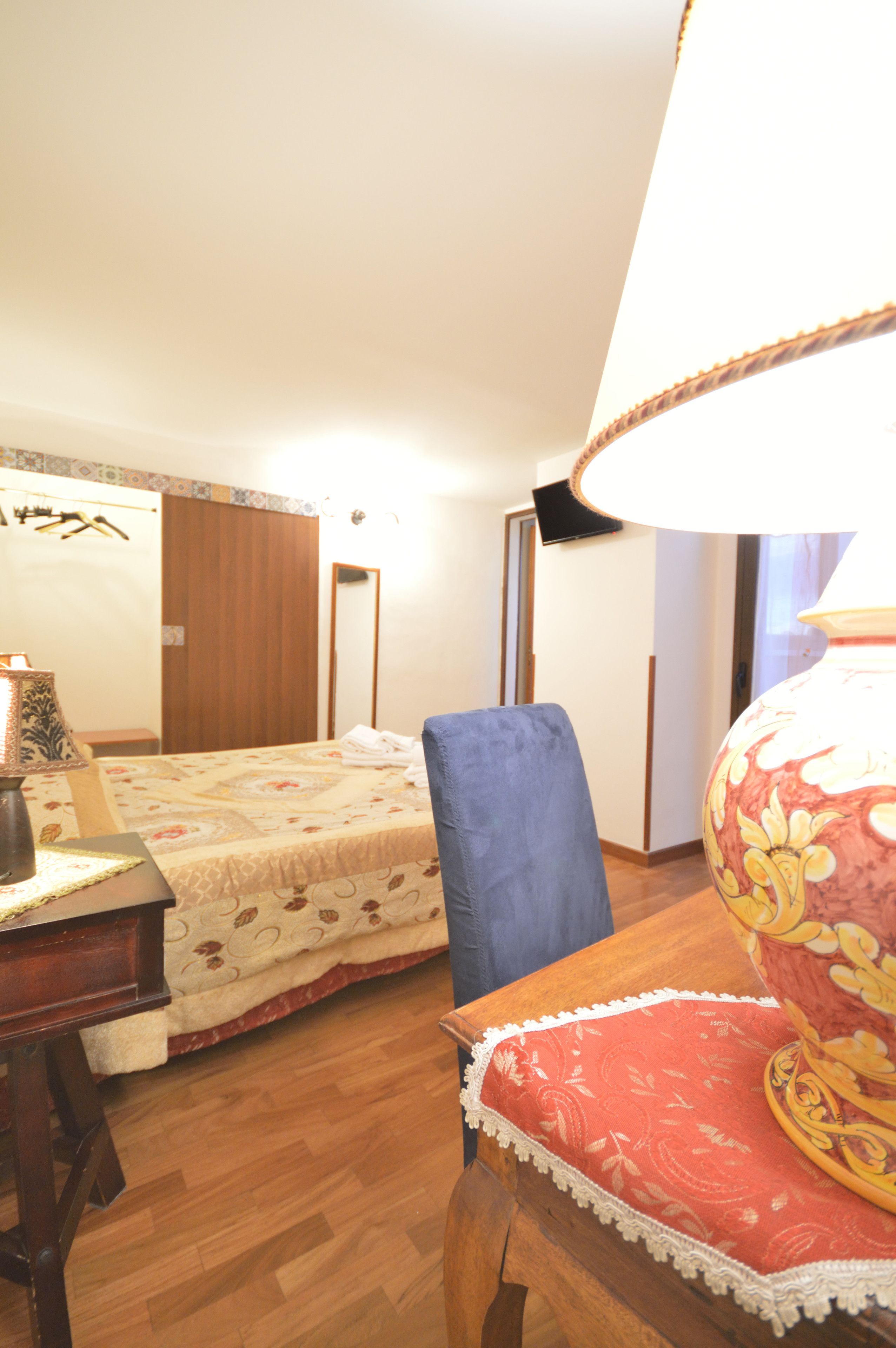 A bedroom with a bed, a desk, a chair, and a lamp.
