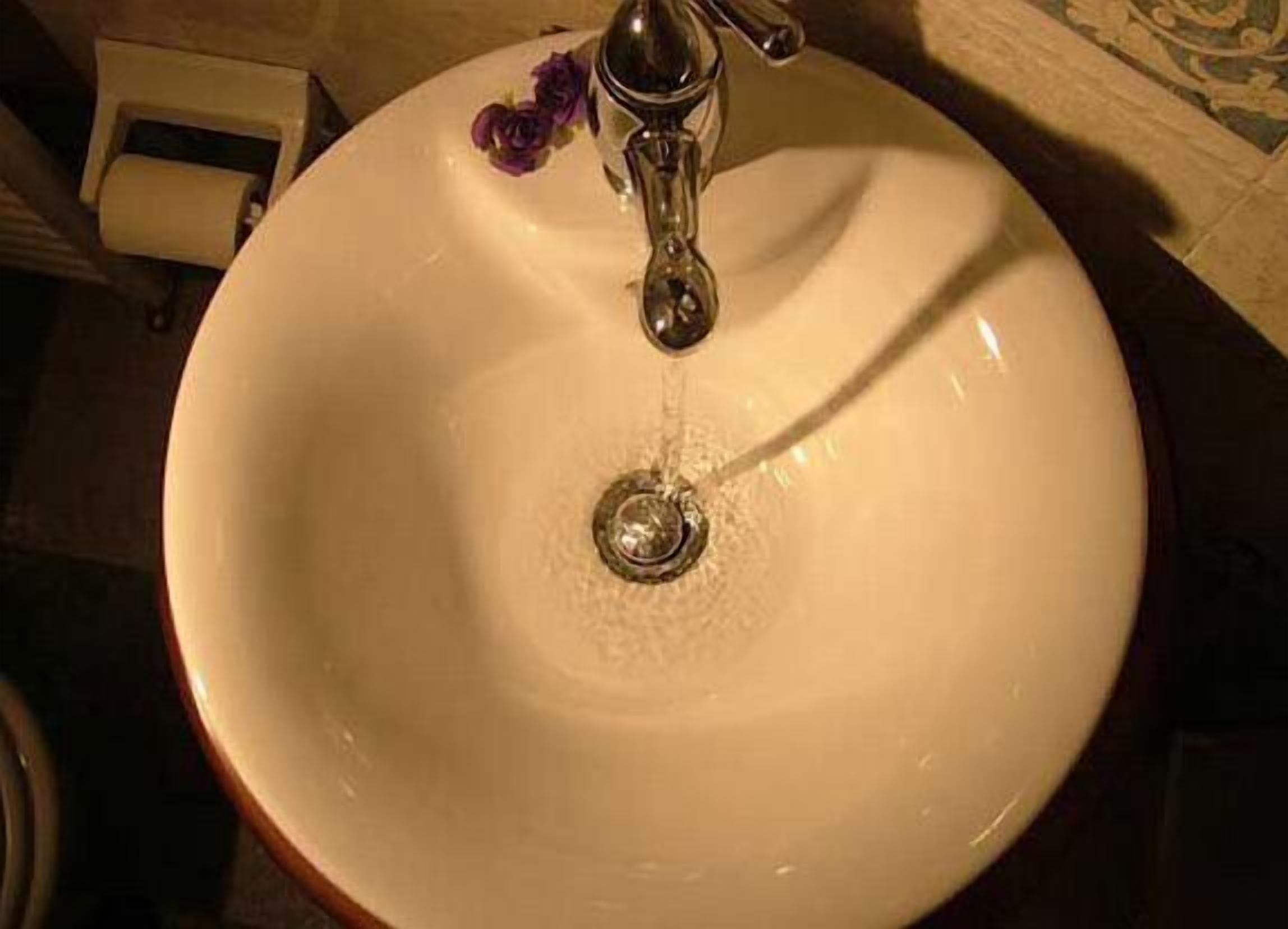 Un évier blanc avec un seul robinet et un drain.