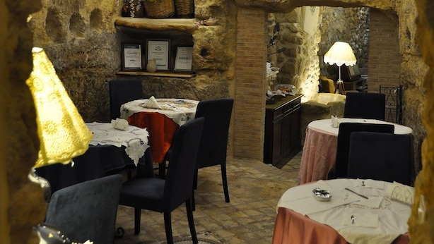 A rustic dining area with stone walls, tables with white tablecloths, and chairs. - B&B Proserpina (Enna)