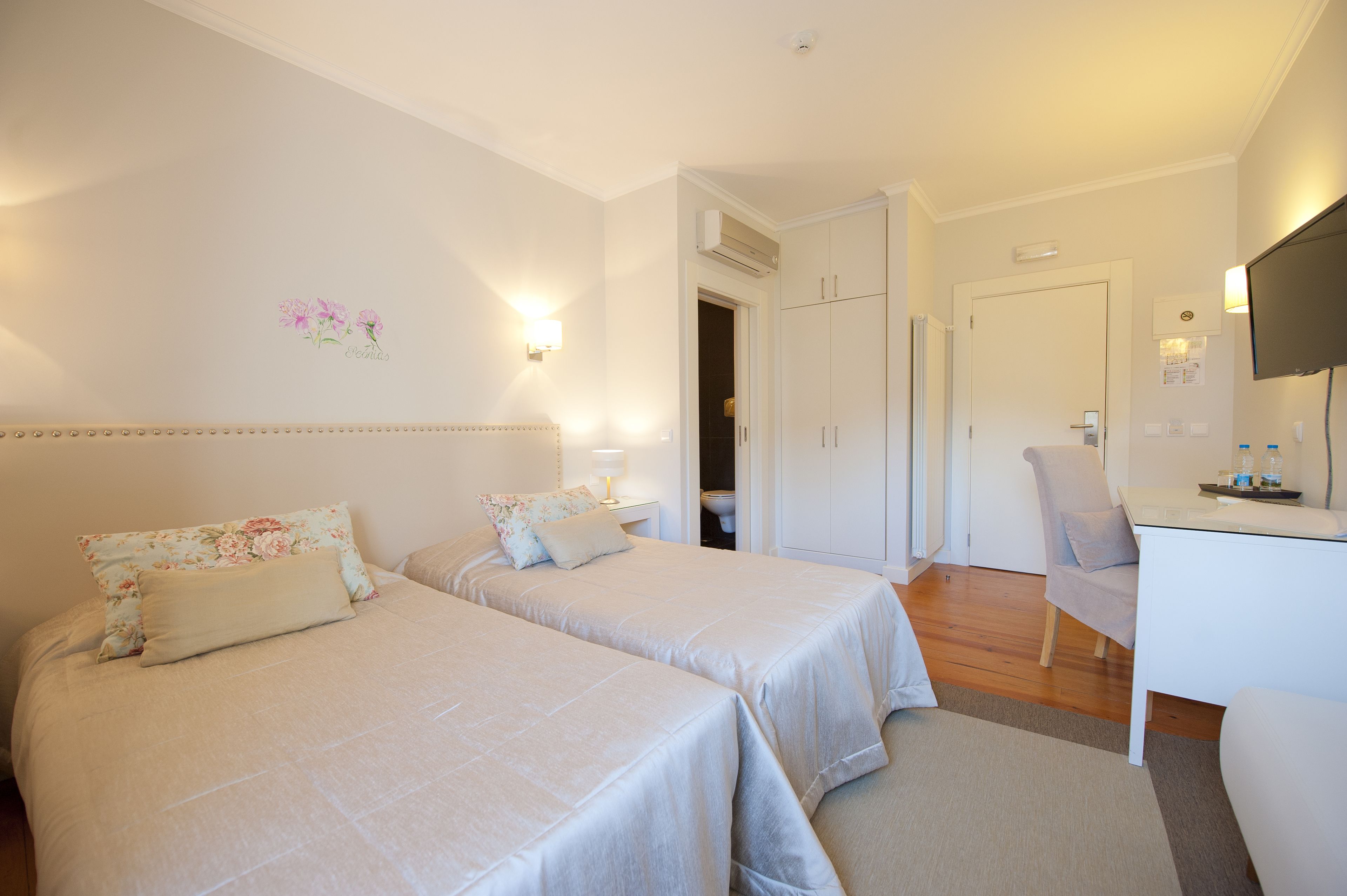 A hotel room with two beds, a desk, and a chair.