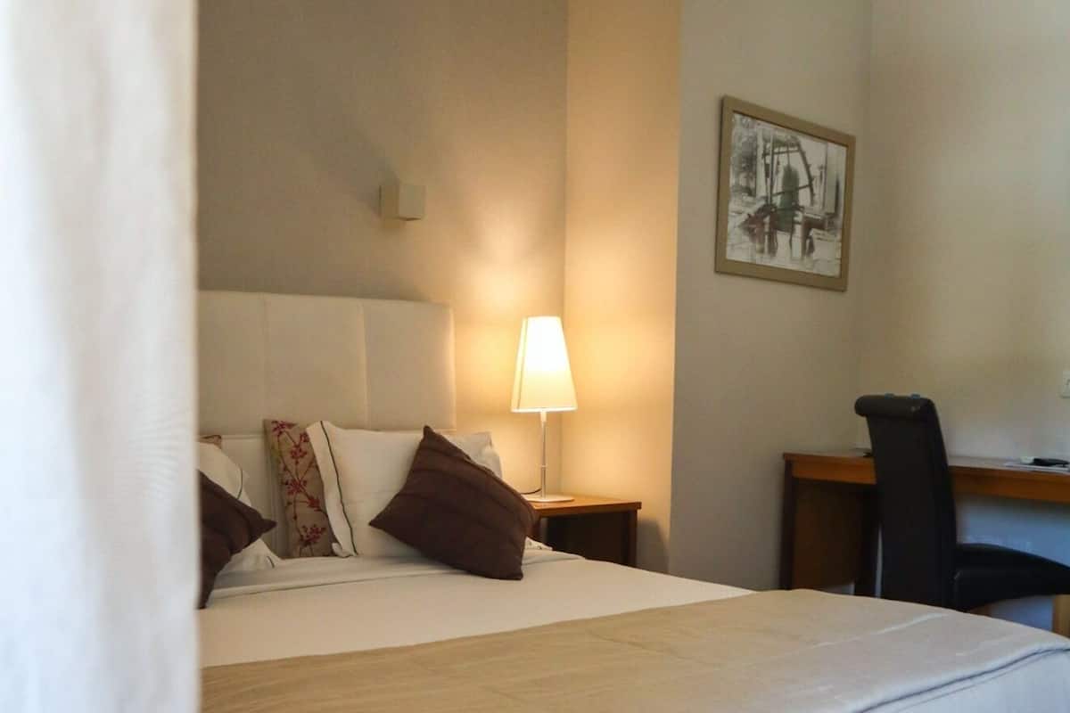 Ein Hotelzimmer mit einem großen Bett, einem Schreibtisch und einem Sessel.