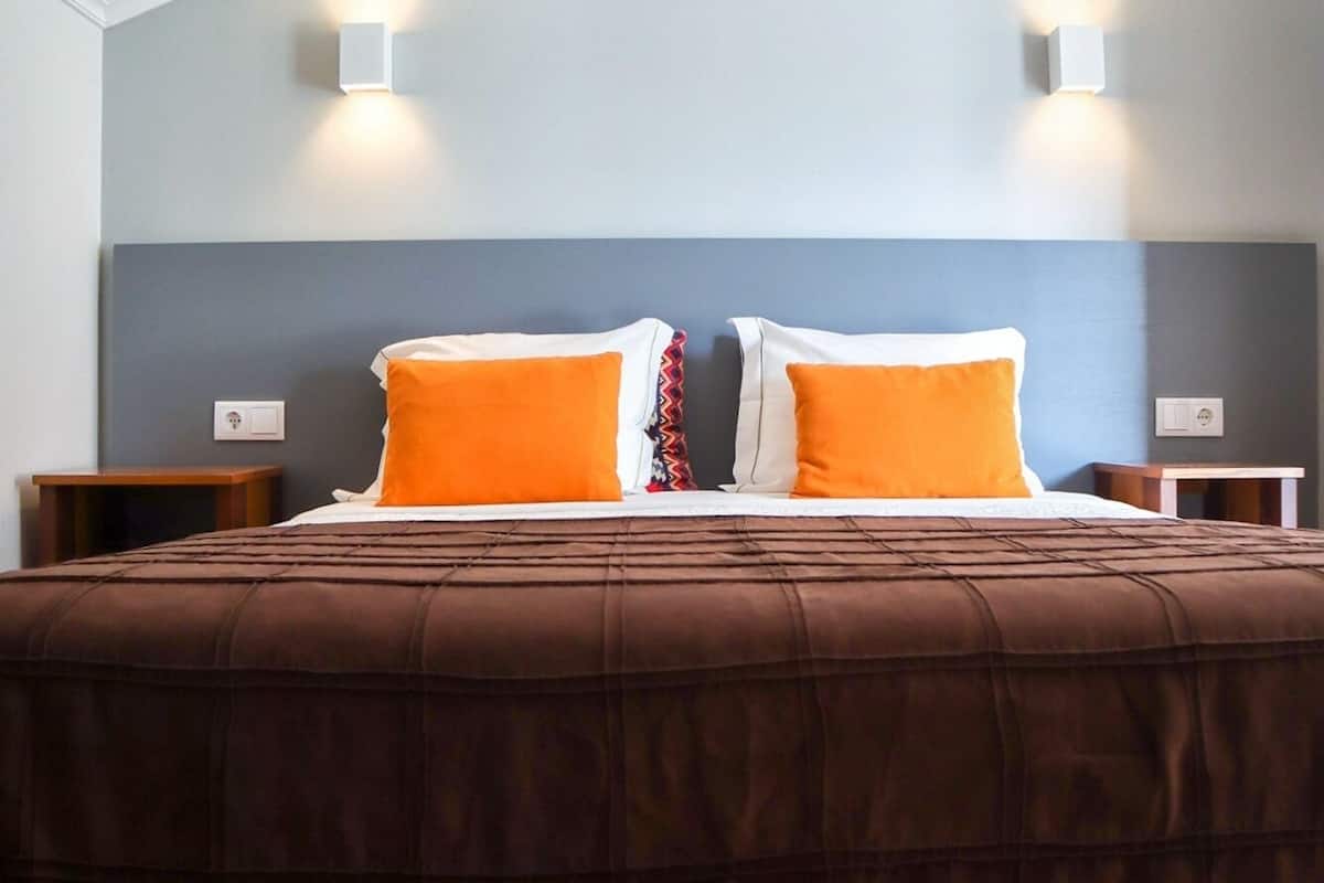 Ein Schlafzimmer mit einem großen Bett, zwei Nachttischen und zwei Wandleuchten.