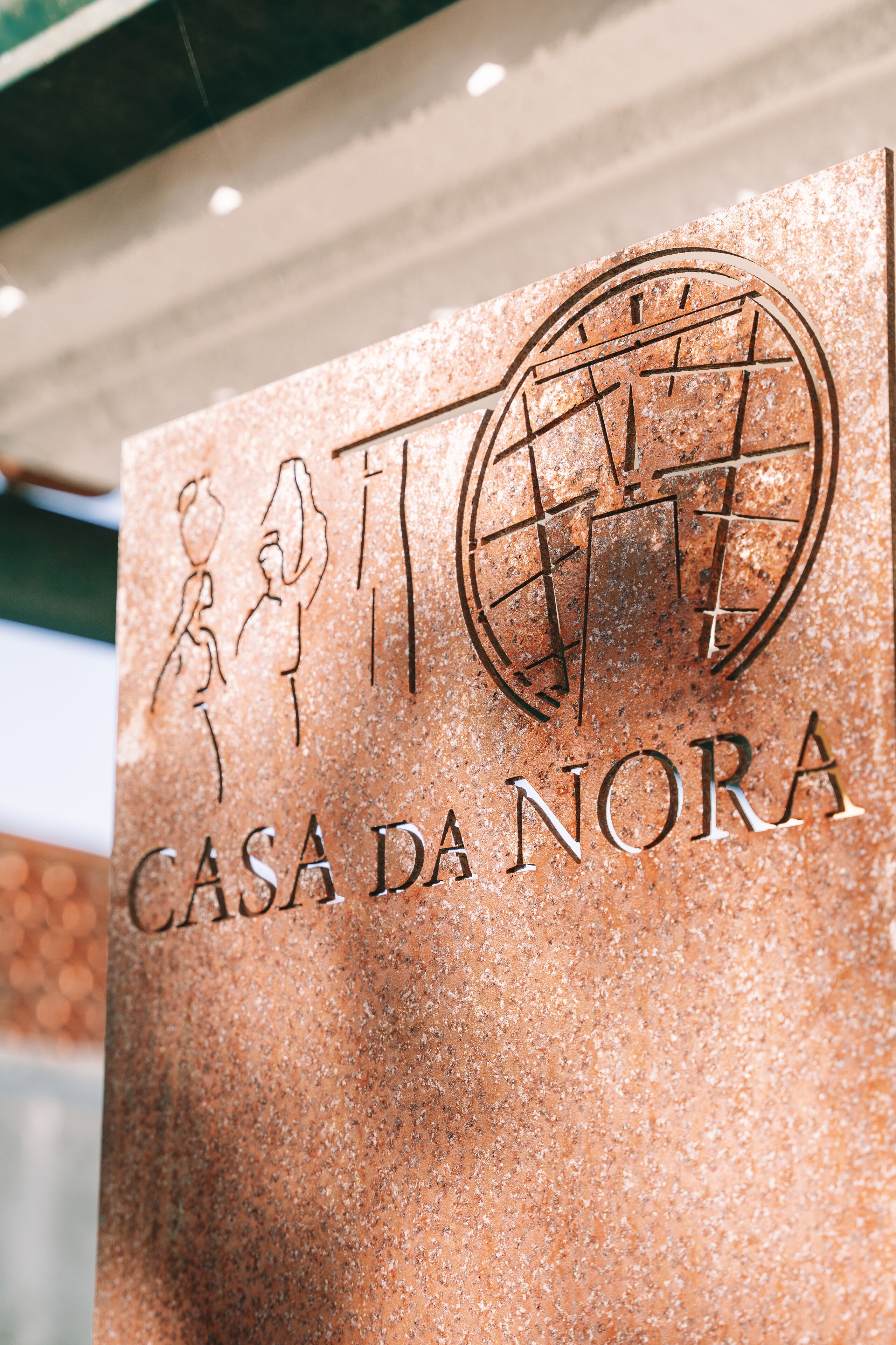 A sign with the text "CASA DA NORA" and a decorative emblem.
