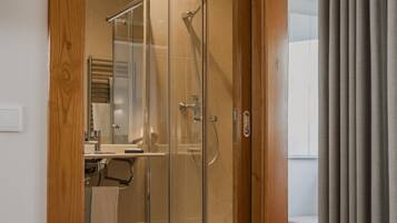 Een hotelkamer met een douche, een bed en een raam met gordijnen.