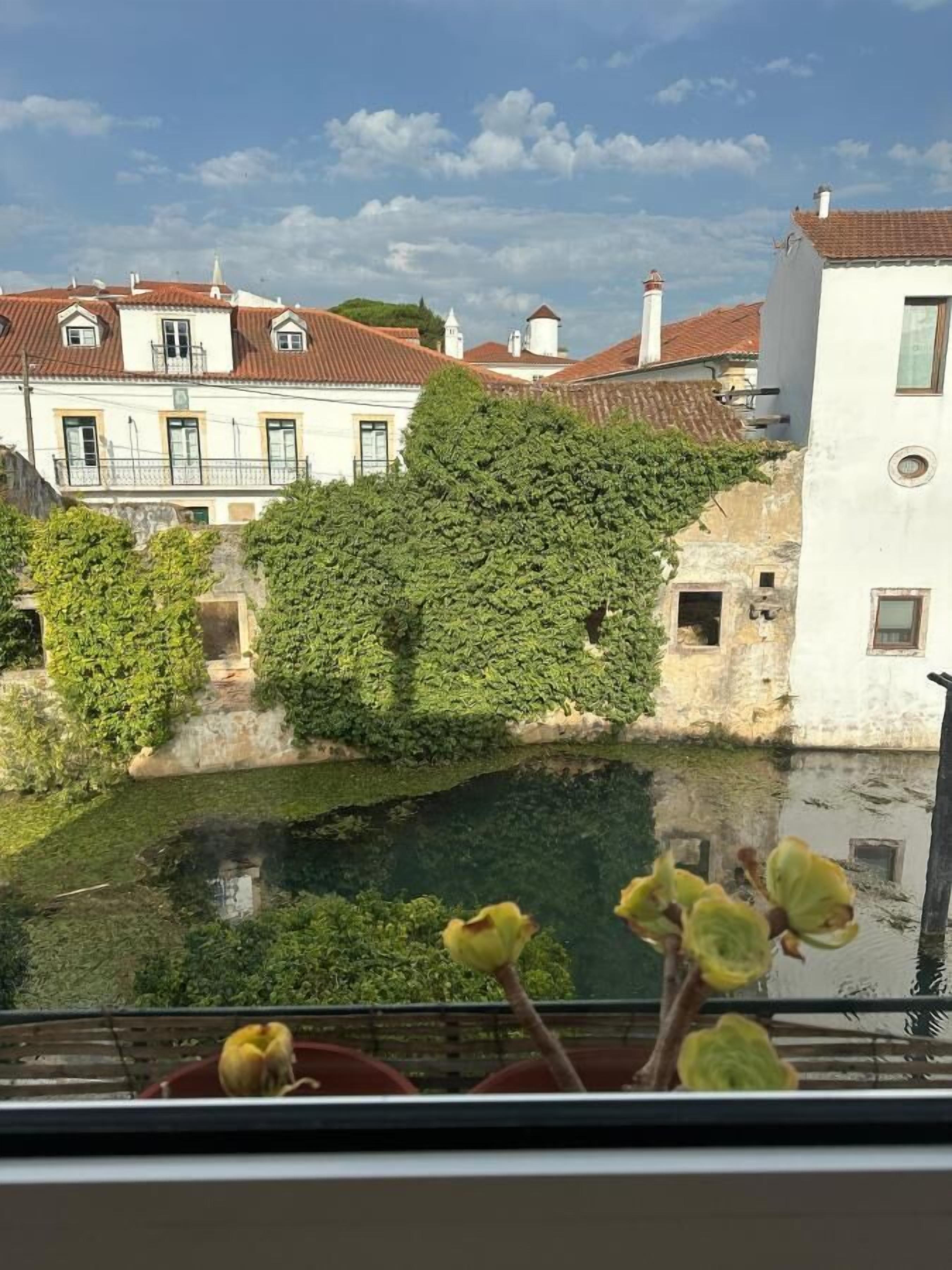 Vista de un patio con fuente, rodeado de edificios con tejados rojos y paredes blancas.