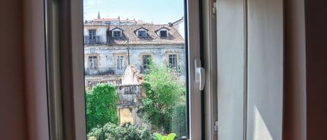 A window with a view of a building with multiple stories and a tiled roof.