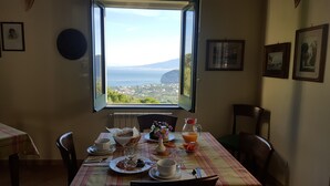 A dining table with breakfast items and a view of a coastal landscape through an open window.