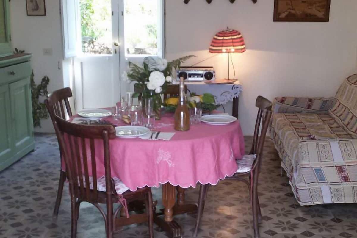 Un comedor con una mesa dispuesta para cuatro personas, una araña y una radio en la pared.