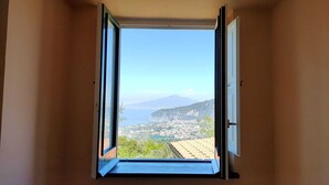 A room with an open window revealing a cityscape and mountains.