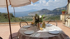 A table set for dining with a scenic mountain view, a potted plant, and a bottle of olive oil.