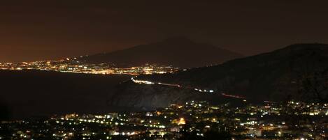 Une vue nocturne d’une ville, avec une montagne en arrière-plan.