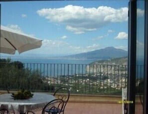 A balcony with a table and chairs, a view of the sea and a distant mountain, and a timestamp indicating the photo was taken on 10/07/2016.