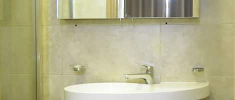 A bathroom with a white sink, a mirror, and a shower.