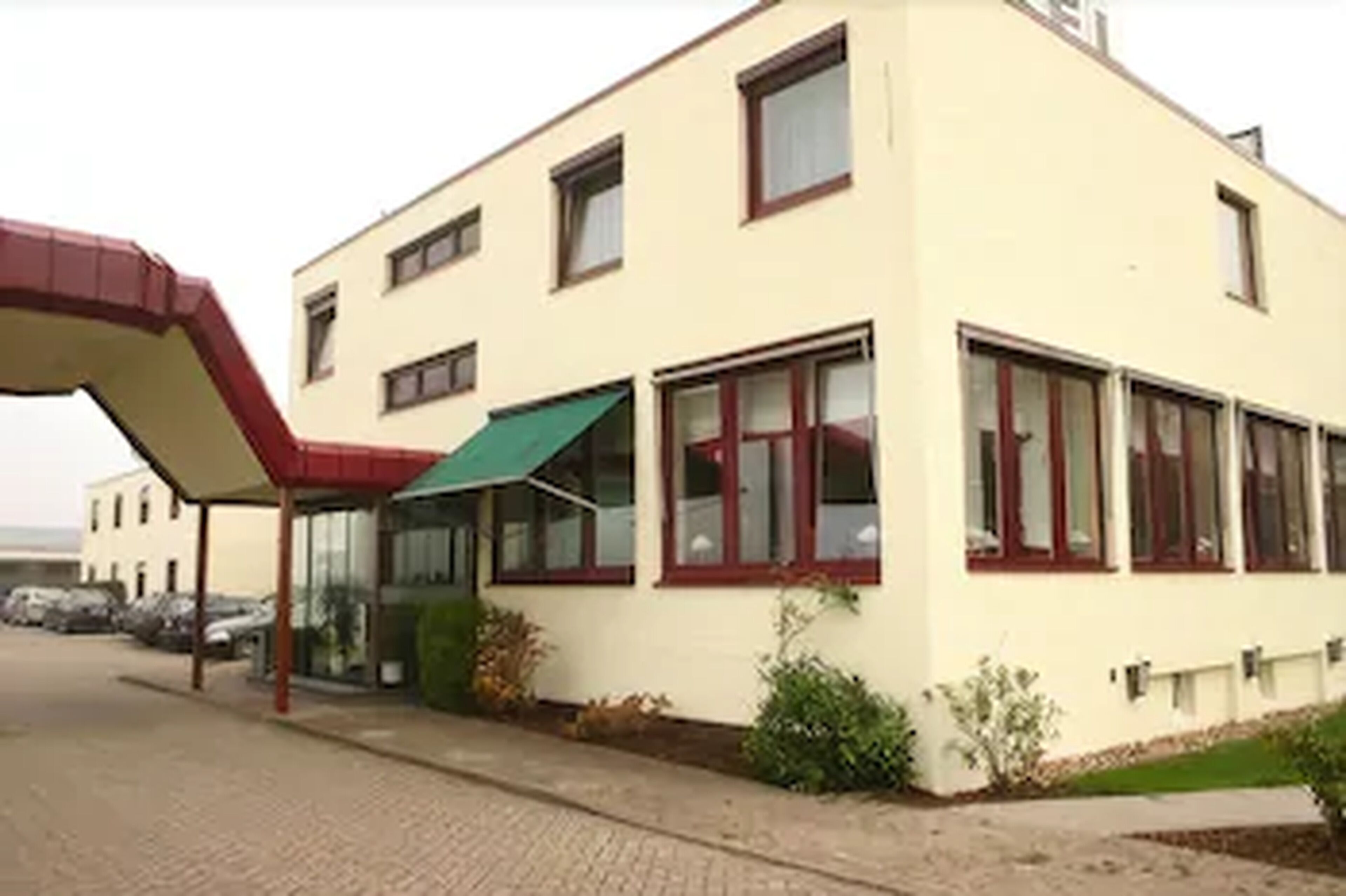 Un edificio de dos pisos con techo plano, ventanas amplias y una entrada cubierta.