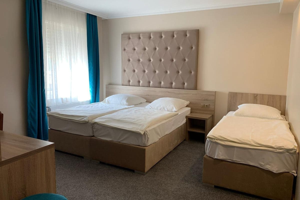 A hotel room with two beds, a wooden desk, and a large tufted headboard.