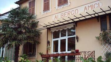 Un edificio con un cartel que dice "AL BERGO AMICI" y una ventana con un letrero que indica "Ristorante".