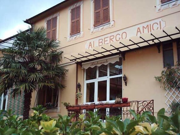 A building with a sign reading "AL BERGO AMICI" and a window with a sign "Ristorante". - Albergo Amici (Varese Ligure)
