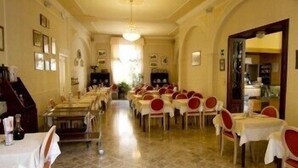 A dining area with multiple tables and chairs, a chandelier, and framed pictures on the walls. - Albergo Amici (Varese Ligure)