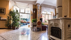 A spacious lobby with a tiled floor, a large fireplace, and several potted plants. - Albergo Amici (Varese Ligure)