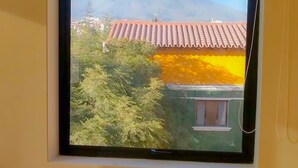 A window with a view of a mountain and a building with red-tiled roofs. - Hotel Villa del Carmen (Arequipa)