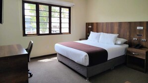 A hotel room with a bed, a desk, a chair, a nightstand, and a window with blinds. - Hotel Villa del Carmen (Arequipa)