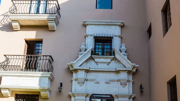 A building with a central entrance, a small balcony, and a staircase leading up to the entrance. - Hotel Villa del Carmen (Arequipa)