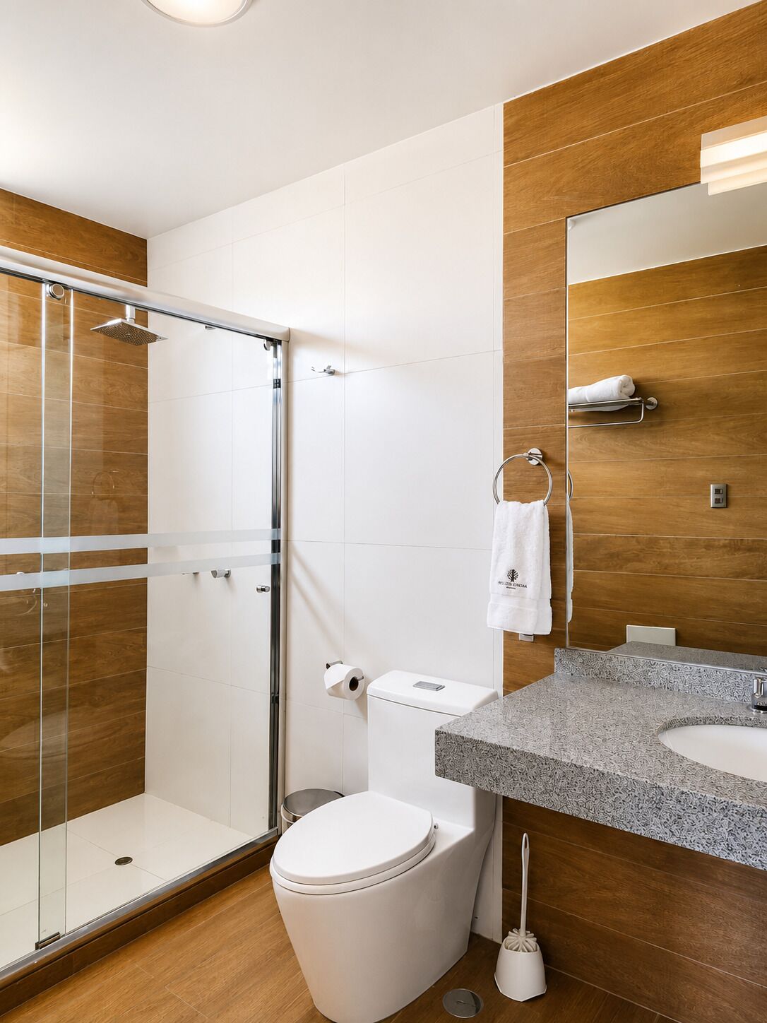 A modern bathroom with a glass-enclosed shower, a toilet, a sink, and a mirror.