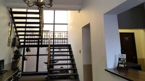 A staircase with a chandelier, a reception desk, and a view of the outside through a window. - Hotel Villa del Carmen (Arequipa)