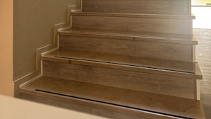 A wooden staircase with a handrail, leading to a landing with a window. - Hotel Irene (Lignano Sabbiadoro)