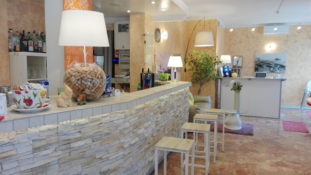 A reception area with a stone wall, a large bottle of wine corks, a floral bowl, and a small rabbit figurine. - Hotel Irene (Lignano Sabbiadoro)
