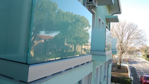 A building with a large glass window reflecting trees and a clear sky. - Hotel Irene (Lignano Sabbiadoro)