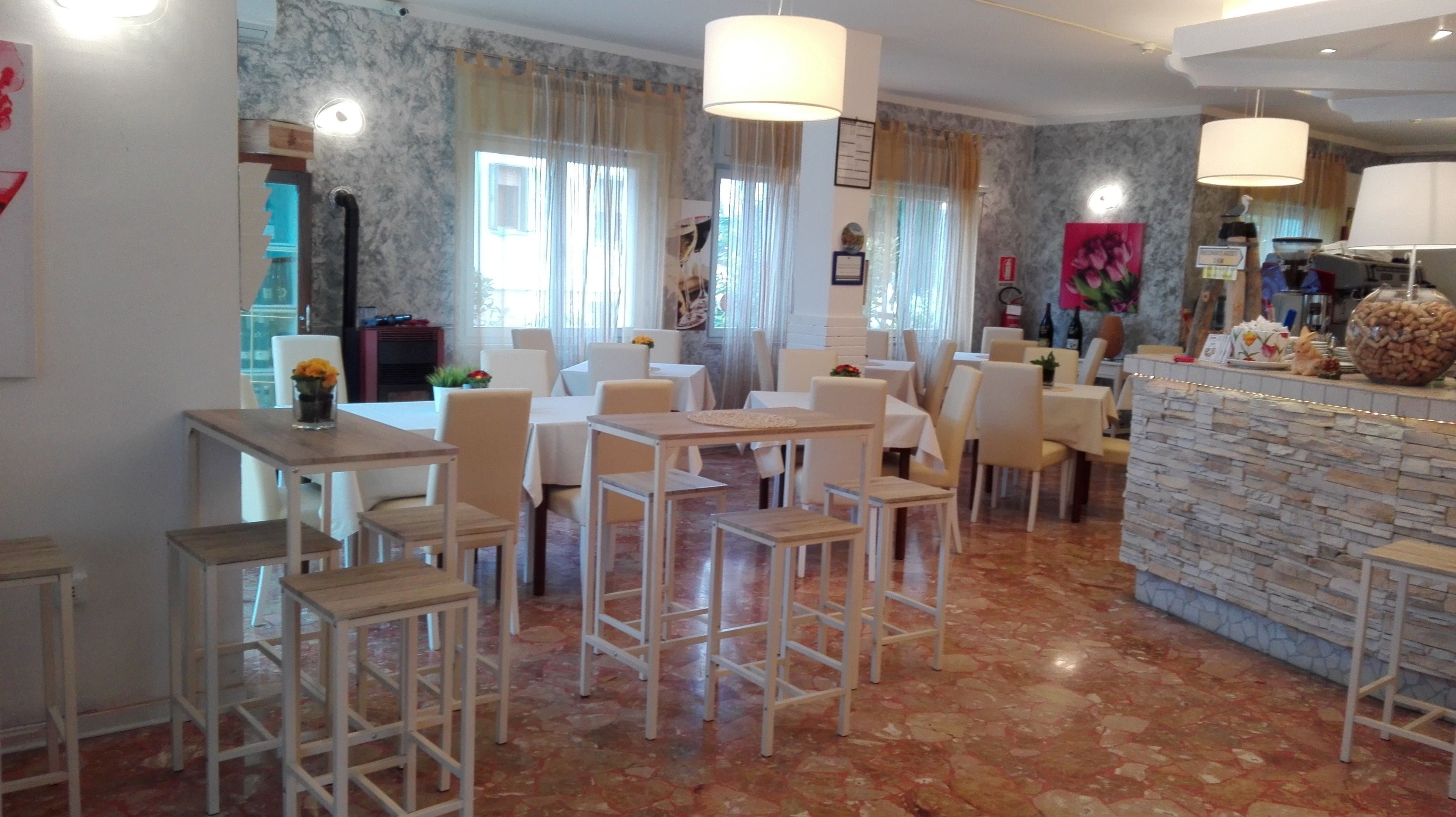 A dining area with white tables and chairs, marble walls, and a stone counter.
