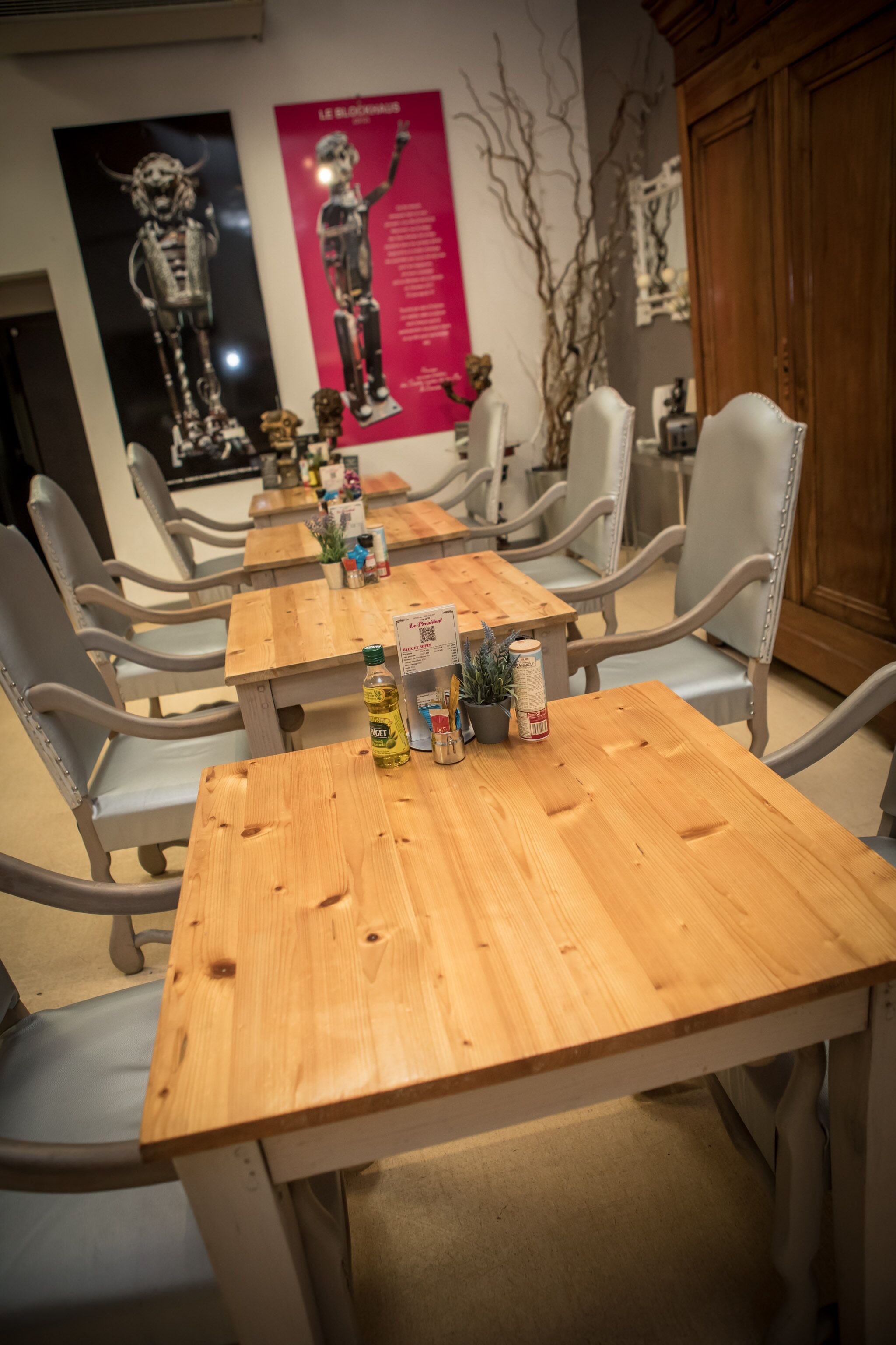 A restaurant with wooden tables and grey upholstered chairs.